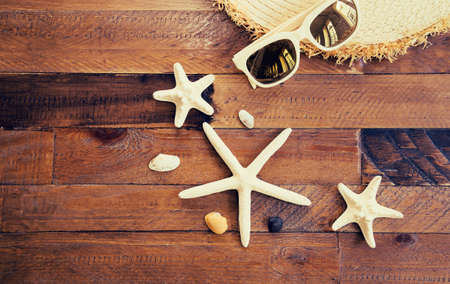 Summer composition with sunglasses, straw hat, starfishes and shells on wooden table. Vacation and travel conceptの写真素材