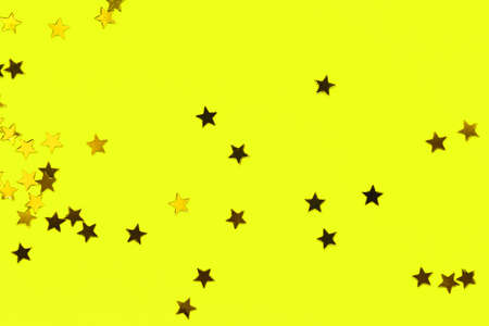 Golden decorative stars on yellow background. Holiday and festive conceptの写真素材