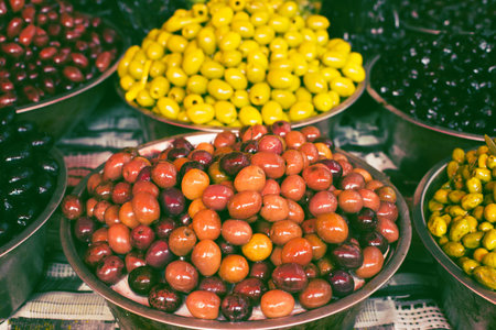Olives in bowls at the market for sale. Traditional mediterranean food suitable for vegans and vegetarians.の写真素材