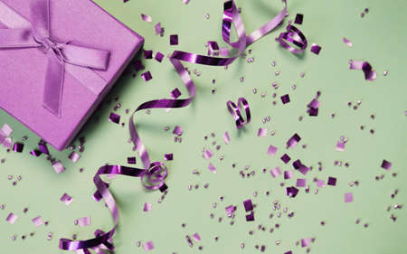Present box on mint background with shiny confetti. Holiday and festive backdrop. Flat lay style. Christmas or birthday gift.の写真素材