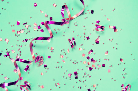Mint background with shiny confetti. Holiday and festive backdrop. Flat lay style. Christmas and...