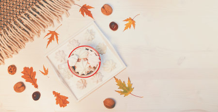 Autumn composition with a cup of meringues, yellow leaves, chestnuts, walnuts and wool blanket on a...