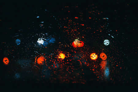 City road seen through rain drops on the car windshield at night. Focus is on some water dropsの写真素材