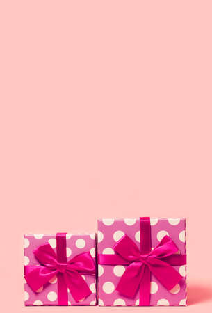 Two present boxes with dots  wrapped with bright ribbon on colorful background. Festive and holiday theme. Christmas or birthday gift. Sales and shopping concept.の写真素材