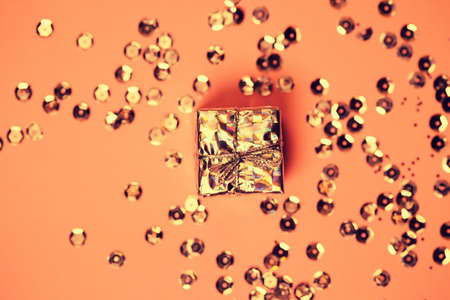 Small decorative present box and sequins on colorful background. Christmas or birthday gift. Celebration and party concept. Flat lay. Top viewの写真素材
