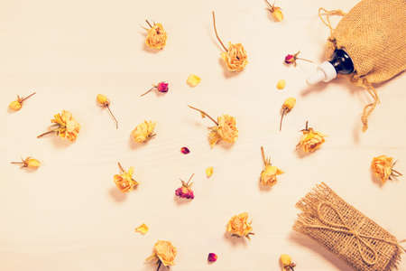 Set of natural soap and aroma oil  with dried rose buds as a decoration on wooden background. Home spa concept. Beauty rituals theme.の写真素材