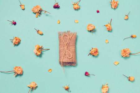 Natural soap with dried rose buds as a decoration on colorful background. Home spa concept. Beauty rituals theme.の写真素材