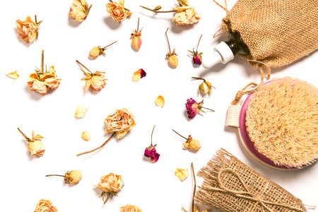 Set of natural soap, aroma oil and body brush with dried rose buds as a decoration on wooden background. Home spa concept. Beauty rituals theme.の写真素材