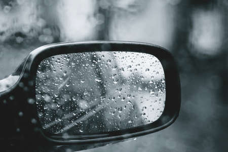 City road seen through rain drops on the car windshield. Focus is on some water dropsの写真素材