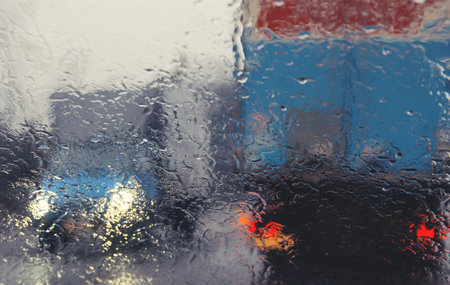 City road seen through rain drops on the car windshield. Focus is on some water drops