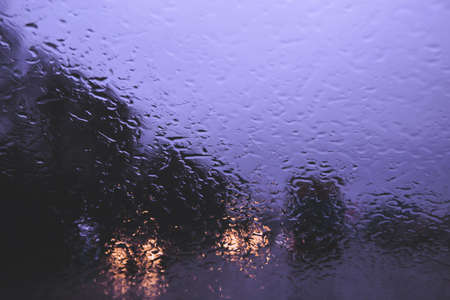 City road seen through rain drops on the car windshield. Focus is on some water dropsの写真素材
