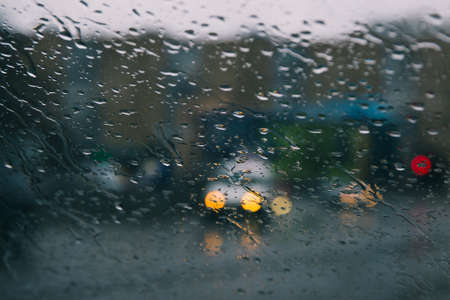 City road seen through rain drops on the car windshield. Focus is on some water dropsの写真素材