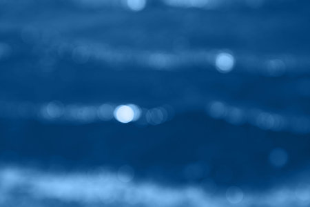 Defocused water background with bokeh  lights. Abstract blurry backdrop of waves. Holiday concept inspired of blue color of 2020.の写真素材
