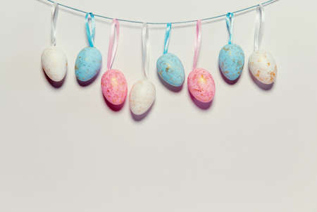 Decorative easter eggs hanging on a strip next to white background. Holiday backdrop for seasonal cards, blogs and web design. Minimal styleの写真素材