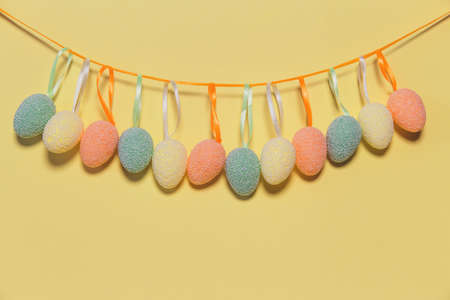 Decorative easter eggs hanging on a strip next to colorful pastel background. Holiday backdrop for seasonal cards, blogs and web design. Minimal styleの写真素材