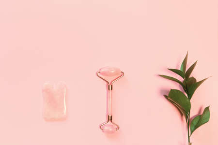 Facial massage kit. Face roller and gua sha massager made from natural stones on pastel pink background. Skin care conceptの写真素材