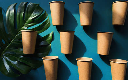 Eco friendly craft paper cups on green background with monstera leaf. Recycling concept. Zero waste themeの写真素材