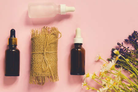 Set of natural soap, essential or aroma oil in bottles and herbs on pastel background. Home spa concept. Beauty rituals theme.の写真素材