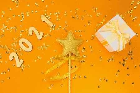 Christmas composition with decorative golden star, present box and 2021 figures on colorful background with sequins.Celebration and party concept. Top view. Flat layの写真素材