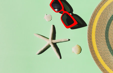 Summer composition with red trendy sunglasses, hat, starfishes and shells on colorful background....
