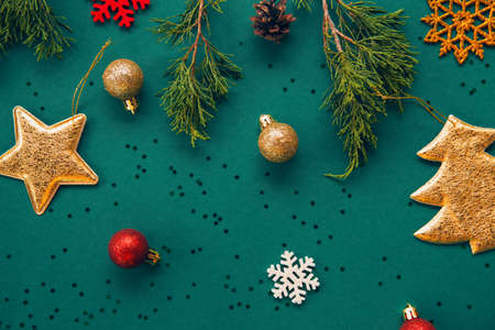 Christmas composition with decorative golden star, fir tree, balls and snowflakes on green background with sequins. Celebration and party concept. Top view. Flat layの写真素材