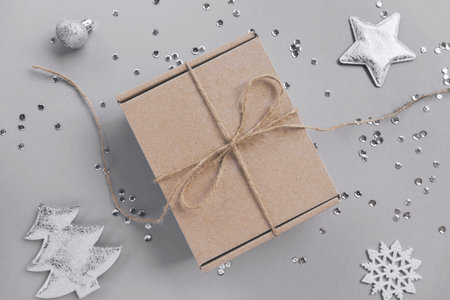 Craft present box on pastel background with decorative fir tree, balls, silver snow flakes, stars...