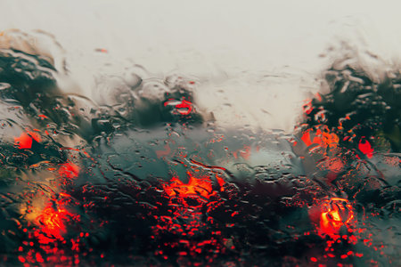 City road seen through rain drops on the car windshield. Focus is on some water drops