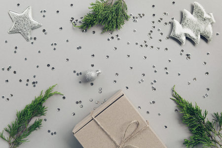 Craft present box on pastel background with juniper branch, decorative fir tree, balls, stars and...