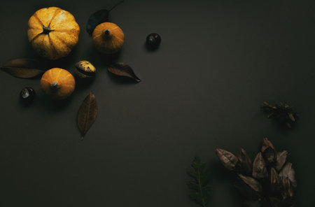 Autumn composition made of pumpkins, dried leaves, chestnuts on brown background. Autumn, fall,...