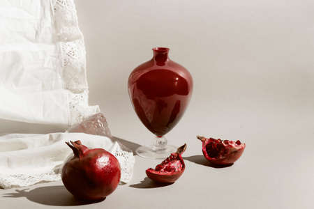 Pomegranates with a vase in light on pastel background. Beautiful backdrop for cards, blogs, posters and web design. selective focusの写真素材