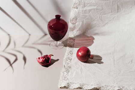 Pomegranates with a vase in light on pastel background. Beautiful backdrop for cards, blogs, posters and web design.の写真素材