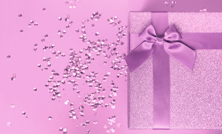 Big present box with bow on a colorful background with sequins. Christmas or birthday gift....