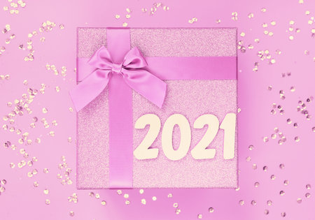 Big present box with bow on a colorful background with sequins. Christmas gift. Celebration and...