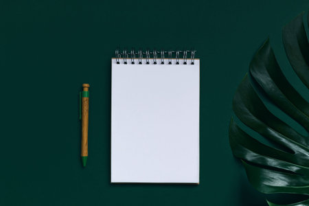 Notepad made of crafted paper with a pen on green background with monstera leaf. Love and romance theme. Eco friendly materials concept.の写真素材