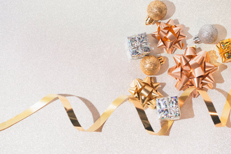 Decorative present boxes, balls, golden streamer and decorative bows on white glittering background. Party and festive concept. Top view. Flat lay.の写真素材