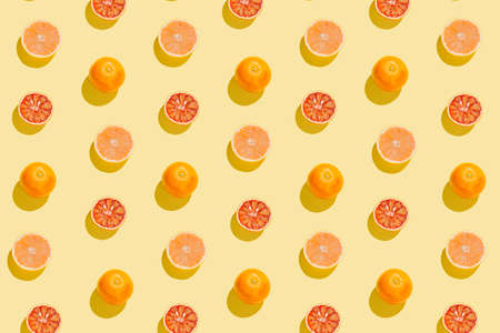 Creative pattern made with sliced grapefruit and blood orange on yellow background. Summer fruit concept. Minimal style. Sunlit flat lay. Top viewの写真素材