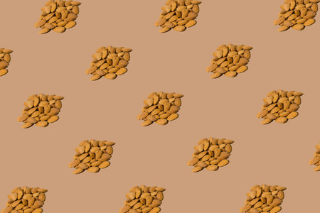 Creative pattern made with almond nuts on beige background. Healthy food ingredient concept .Minimal...