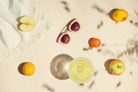 Summer still life composition made of fruits, glass with juice and sunglases on pastel background...