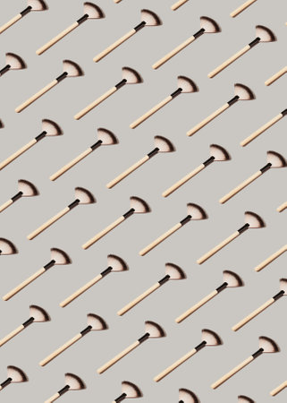 Creative pattern made with make up brushes on pastel gray background. Decorative cosmetics and makeup concept. Minimal style composition.の写真素材