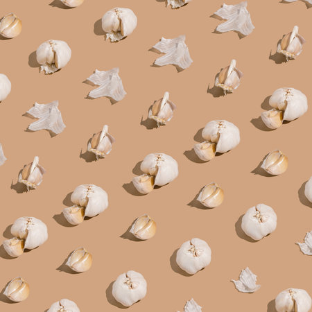 Creative pattern made with garlic on beige background. Healthy food ingredient concept .Minimal style.の写真素材
