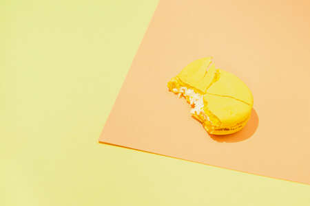 Bite yellow macaroon on colorful geometric background. Minimal style composition. Abstract backdropの写真素材