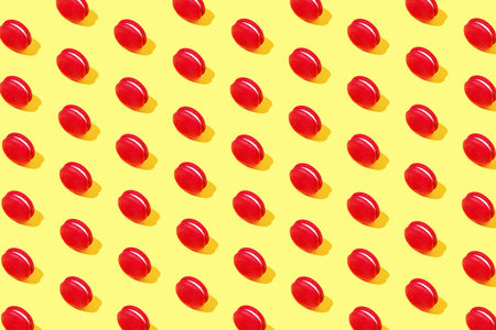 Creative pattern made of red macaroons on yellow background. Dessert and confectionary concept.