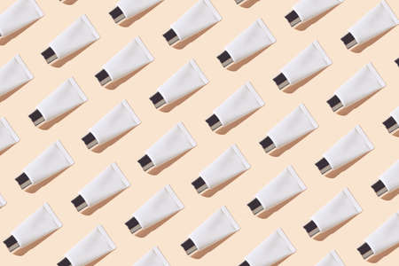Creative pattern made of white cosmetic tube on pastel background with sunlit. Skincare concept. Minimal styleの写真素材