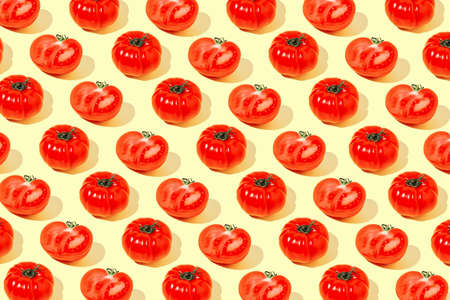 Creative pattern made of fresh raw red tomatos on pastel yellow background. Healthy food concept.の写真素材