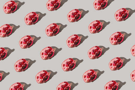 Creative pattern made of fresh slices of pomegranate on pastel gray background with sunlit. Minimal style. Top view. Flat lay.の写真素材