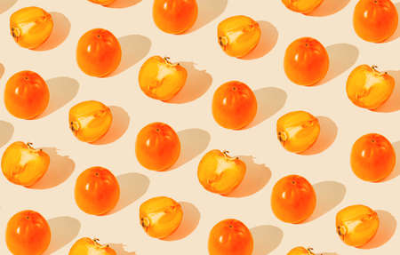 Creative pattern made of persimmon fruits on pastel background with sunlit. Healthy food conceptの写真素材