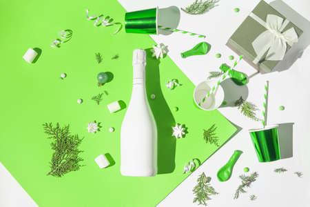 Christmas composition made of white champagne bottle, paper glasses with straws, present box, meringues and green baubles. Festive and party concept. 2022 new year background.の写真素材