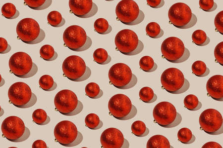 Simple pattern made of red baubles on pastel background. Creative winter composition. Christmas party and festive concept. Minimal style.の写真素材