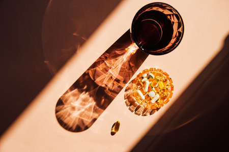 Pills on a small plate and glass of water on sunlit background. Health care concept. Morning routine theme. Top viewの写真素材