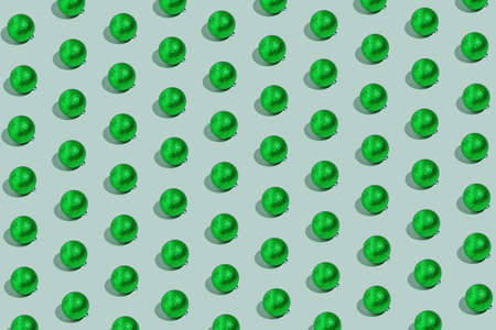 Simple pattern made of green baubles on pastel background. Creative winter composition. Christmas party and festive concept. Minimal style.の写真素材